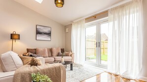 A living room with a sofa set, a coffee table, a lamp, and a view through a sliding glass door to the outside. - Hallgarth Street  (Sherburn Village)