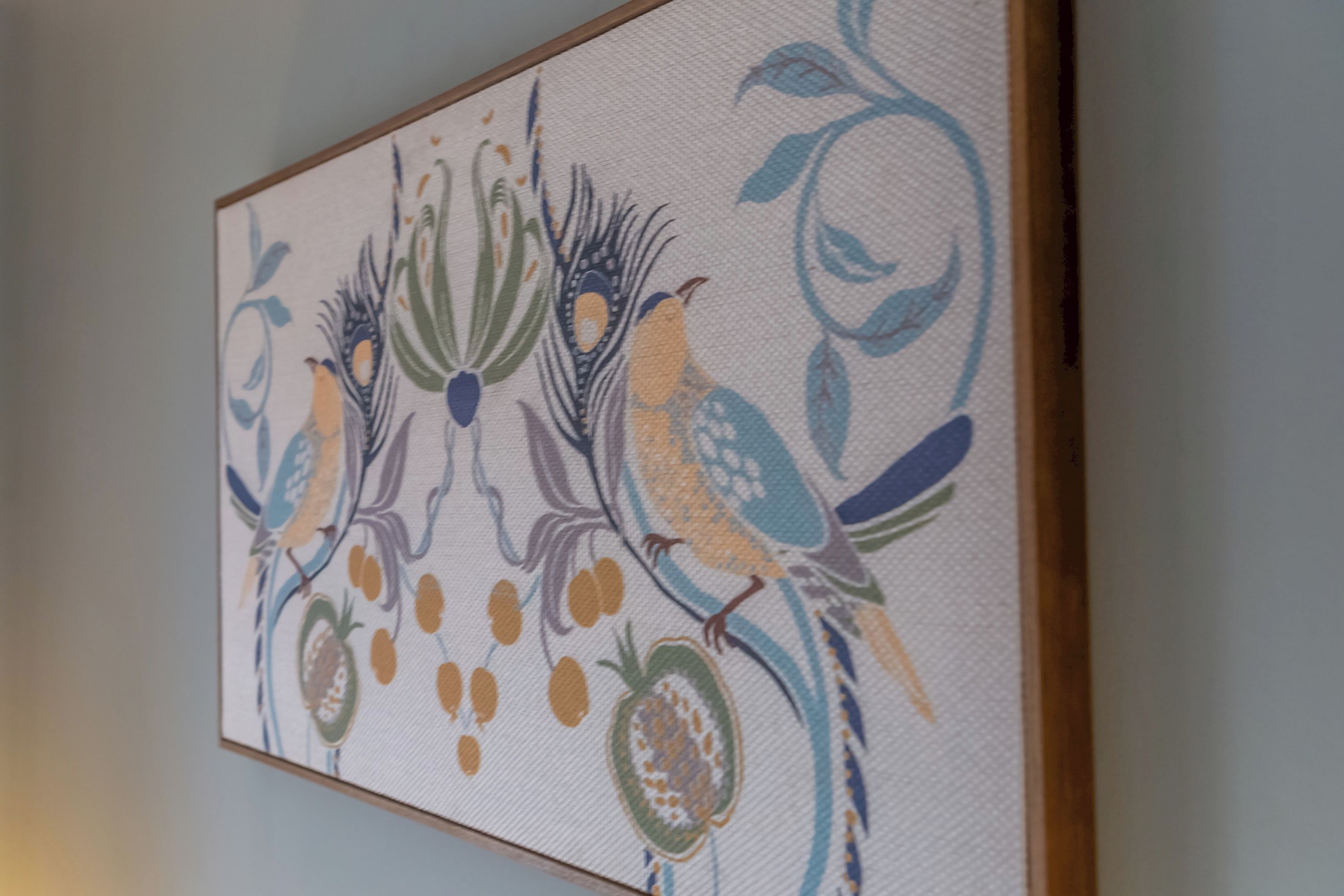 Una obra de arte enmarco con motivos florales y de aves abstractos.