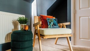 A cozy room with a wooden chair, a green ottoman, and a potted plant. - Hallgarth Street  (Sherburn Village)