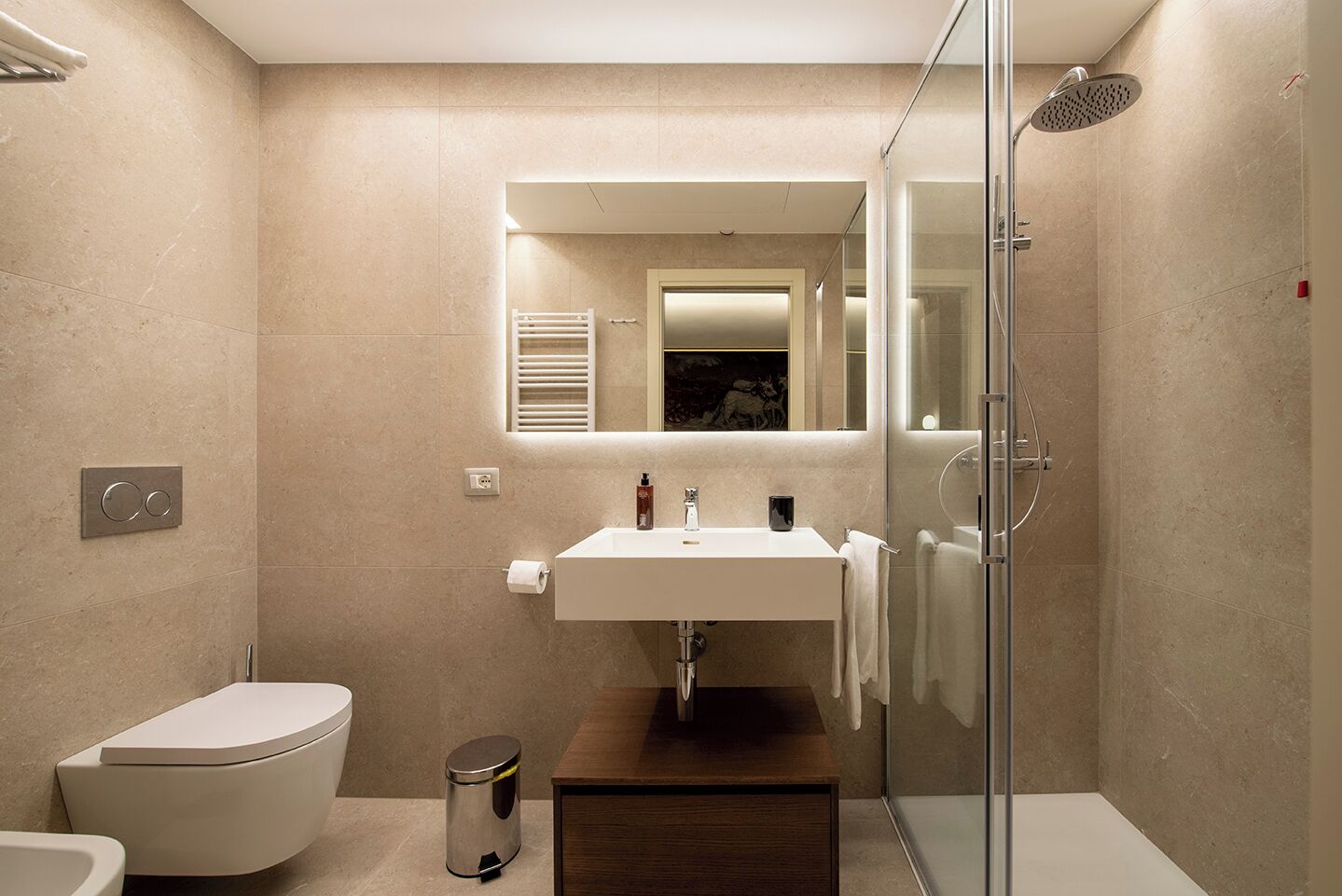 A modern bathroom with a glass-enclosed shower, a white sink, and a toilet.