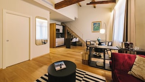 A modern living room with a wooden floor, a red sofa, a black coffee table, and a dining area with a table and chairs. - Palazzo Confalonieri da Lisca (Verona)