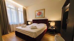 A hotel room with a large bed, two bedside tables with lamps, a painting on the wall, and a wooden floor. - Palazzo Confalonieri da Lisca (Verona)
