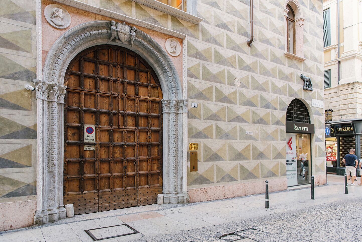 A historic building with a large wooden door, a stone facade, and a sign for 'BIALETTI' and 'LIBRERIA'.