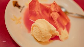 A plate with a scoop of ice cream and a piece of fruit on a red tablecloth. - G.M.T. Sorabora Village Hotel (Mahiyanganaya)