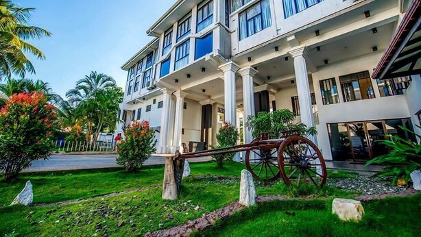 A multi-story hotel with a central courtyard, columns, and a vintage carriage. - G.M.T. Sorabora Village Hotel (Mahiyanganaya)