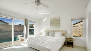 A bedroom with a large bed, a ceiling fan, and a view of a swimming pool. - Villa Solana: Heated Pool, Putting Green, Games (La Quinta)