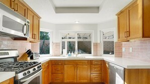 A kitchen with wooden cabinets, a gas stove, a microwave, and a dishwasher. - Villa Solana: Heated Pool, Putting Green, Games (La Quinta)