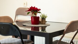Ruokapöydällä on punainen ruukku, pieni kasvi ja koristeellinen aluslakanen.