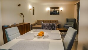 Un salon moderne comprenant une table à manger, deux canapés et un tableau représentant un paysage urbain accroché au mur.