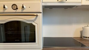 Una cucina con forno bianco, piano cottura integrato e un piano di lavoro in legno.