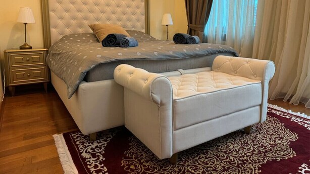 Una camera da letto con un letto grande, un comodino, una sedia e un tappeto decorato.