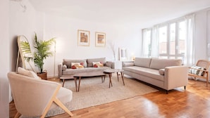 Un salon moderne avec deux canapés, une table basse, un lampadaire et une grande fenêtre.