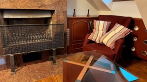 Ein modernes Wohnzimmer mit Kamin aus Stein, einer roten Ledersofa mit gemusterten Kissen und einem Glastisch.