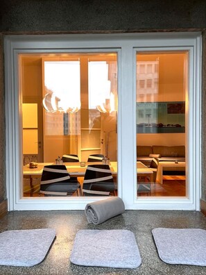 Ein modernes Zimmer mit Essbereich, einer Couch und einem Fenster mit Blick auf Gebäude.