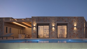 Ein modernes Haus mit Naturstein-Fassade, einem Swimmingpool und einem Essbereich mit Gartenmöbeln.