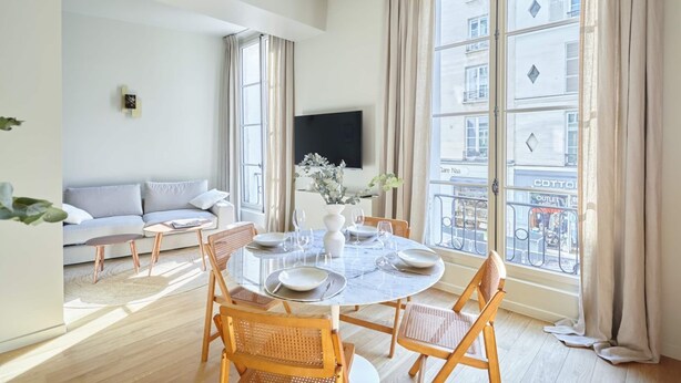 Un salon moderne comprenant un coin repas, de grandes fenêtres, un téléviseur à écran plat et une vue sur la ville.