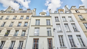 Une rangée de bâtiments de style européen classique, caractérisés par des façades uniformes, de grandes fenêtres et des balcons.