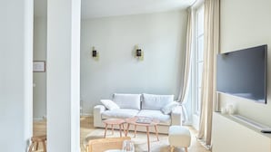 Un salon moderne avec un canapé, une table basse et un téléviseur à écran plat fixé au mur.