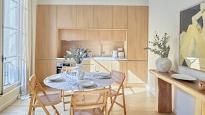 Une cuisine moderne avec des meubles en bois, une table à manger avec des chaises et un vase rempli de fleurs.