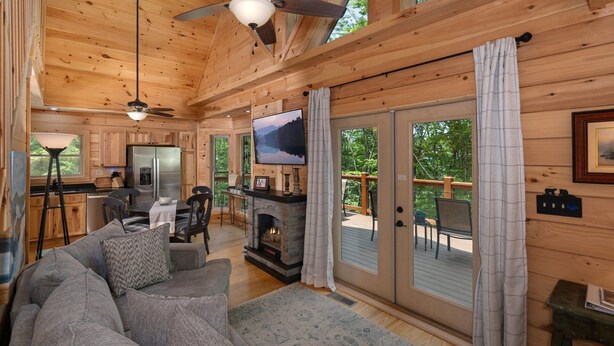 Ein gemütliches Blockhaus-Interieur mit Kamin, einer Couch, einem Essbereich und einem Fernseher.