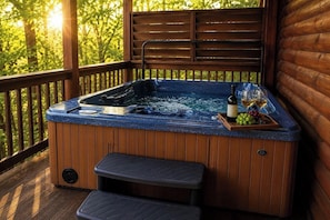 A hot tub with a wooden deck, a wooden bench, and a tray with wine and grapes.