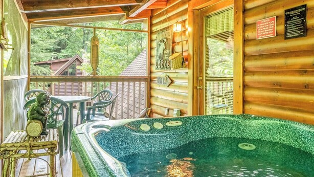 A wooden cabin with a hot tub, a covered deck with chairs, and a sign indicating a lodge. - Eagles Ridge Cabin · Hot Tub, Jacuzzi & Pool Table (Pigeon Forge)