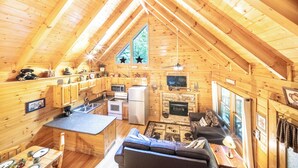 A cozy cabin with a kitchen, dining area, and living room, featuring wooden walls and a sloped ceiling. - Eagles Ridge Cabin · Hot Tub, Jacuzzi & Pool Table (Pigeon Forge)
