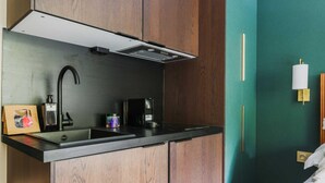 Cozinha compacta com pia preta, cafeteira e exaustor embutido.