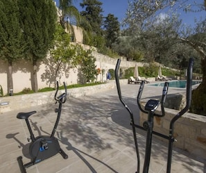 Buitenfitnessapparatuur in een aangelegde tuin bij een zwembad.
