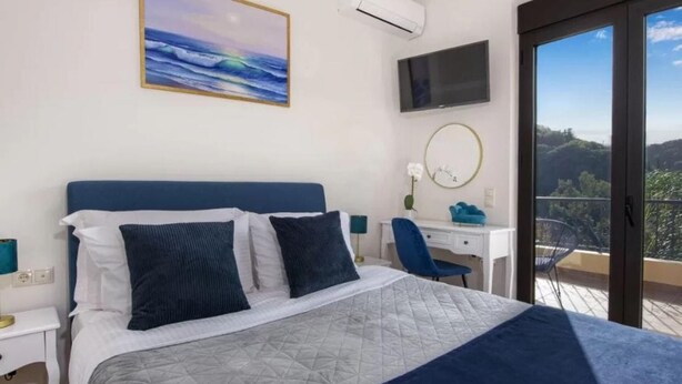 Une chambre d’hôtel avec un lit, un bureau, une télévision et un balcon offrant une vue.