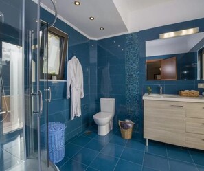 Un baño moderno con cabina de ducha de vidrio, inodoro blanco y tocador de madera con espejo.