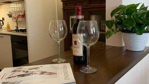 A kitchen counter with two wine glasses, a bottle of Chianti wine, and a magazine titled "FRENZWEILER". - [5 min from Uffizi] Lady Suite in Center, Wifi, Comfort (FLORENCE)