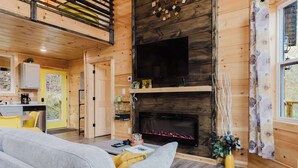 Un acogedor interior de cabaña con sala de estar, cocina y chimenea.