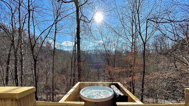 Une terrasse en bois menant à un jacuzzi entouré d’une forêt.