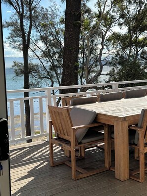Terraza de madera con mesa y sillas con vista al agua.