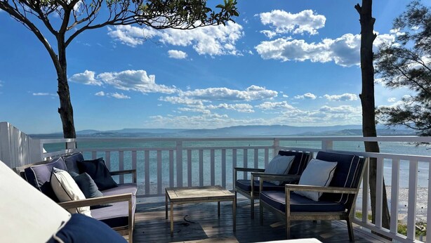 Una terraza con mobiliario exterior, vista al mar y cielo despejado.