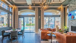 A modern hotel lobby with a pool view, leather sofas, and a fireplace.
