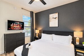 A hotel room with a bed, a TV, a desk, and a window with curtains.