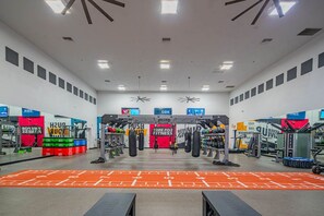 Une salle de sport équipée de divers appareils d’exercice, notamment une barre de traction et des sacs de frappe.