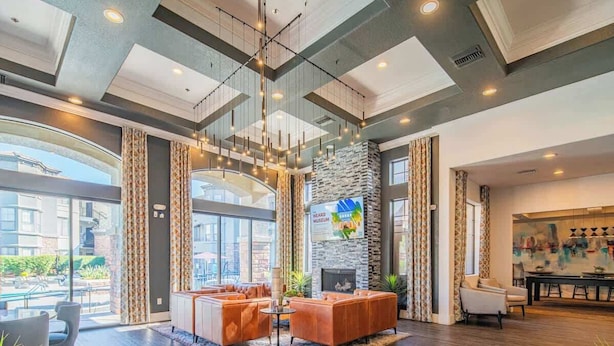 A spacious lobby with a fireplace, comfortable seating, and large windows offering a view of the city.