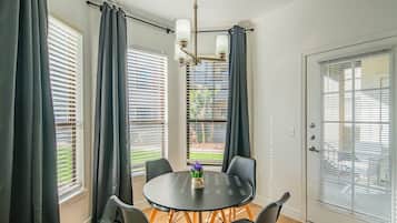 Un coin repas avec une table ronde, quatre chaises et un lustre.