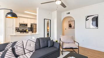 Un salon moderne avec un canapé gris, une table basse noire et un ventilateur de plafond.