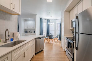 A modern kitchen with a dishwasher, a refrigerator, and a dining area with a table and chairs.