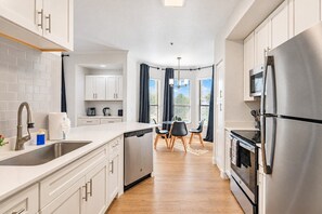 Una cocina moderna con armarios blancos, electrodomésticos de acero inoxidable y una isla central con asientos.