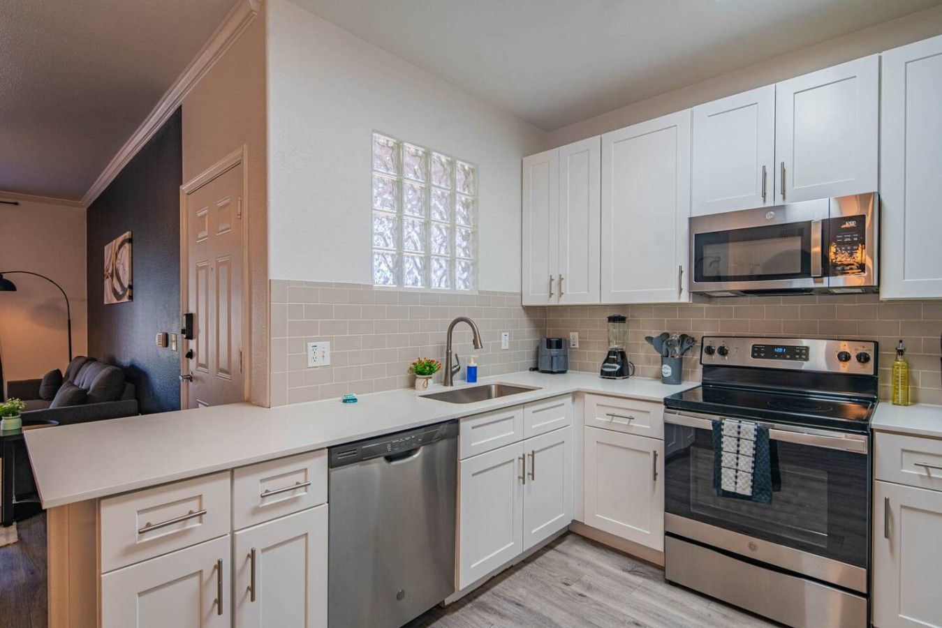 A modern kitchen with white cabinetry, stainless steel appliances, a dishwasher, and a microwave.