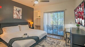 A hotel room with a bed, a ceiling fan, a painting, a TV, and a view of the outdoors. - Near the Stadium with  Pool Gym Parking HotTub WD (Glendale)