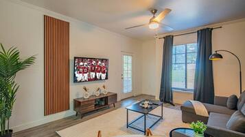 A modern living room with a flat-screen TV, a ceiling fan, a sofa, and a coffee table.