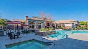 A pool area with lounge chairs and umbrellas, a small pool, and a building with arched windows. - Near the Stadium with  Pool Gym Parking HotTub WD (Glendale)