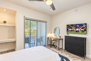Un dormitorio con cama, escritorio con silla, televisor y armario.
