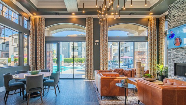 A modern hotel lobby with a pool view, leather sofas, and a fireplace.
